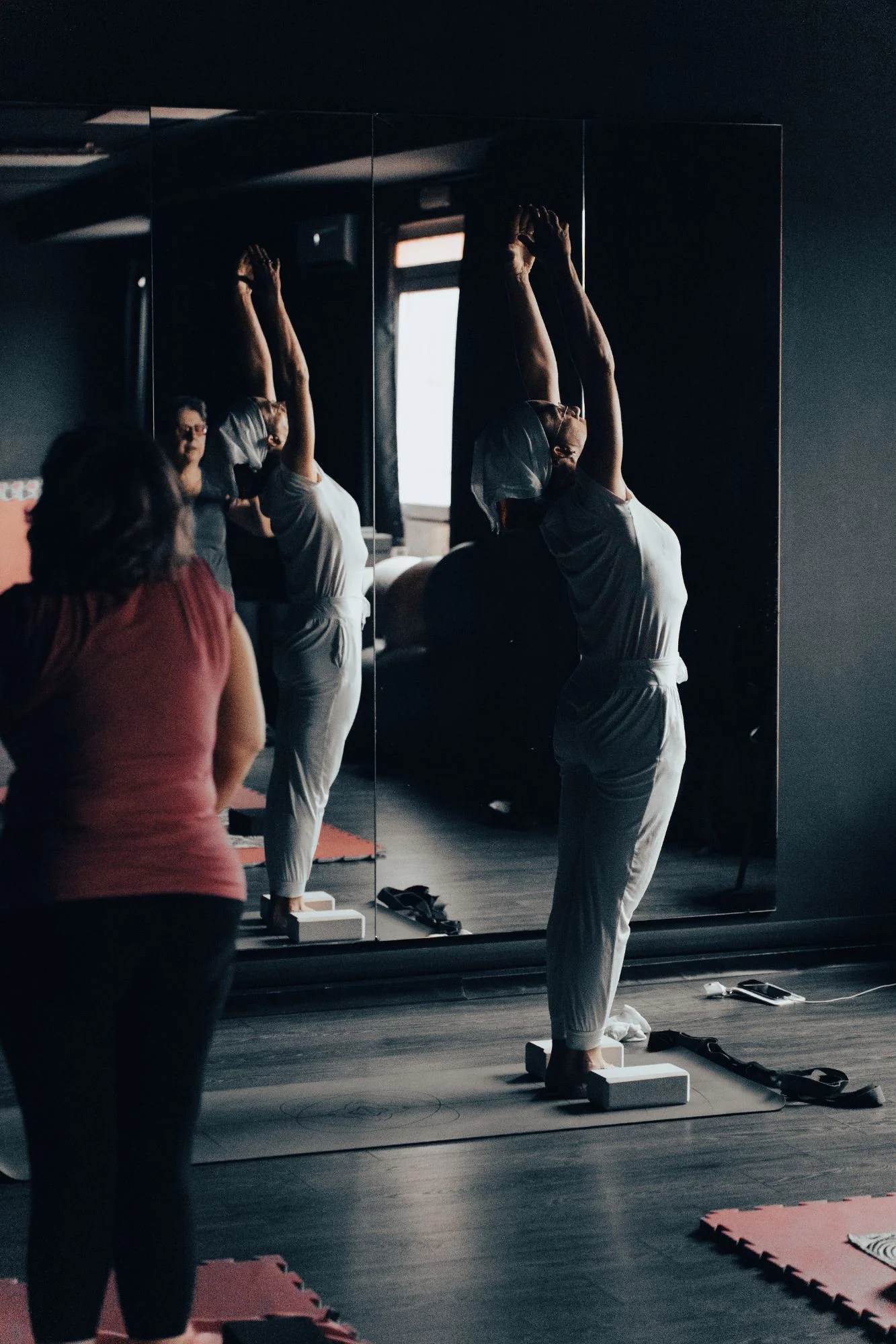 Allieve durante un allungamento in piedi davanti allo specchio in una lezione di Hatha Yoga