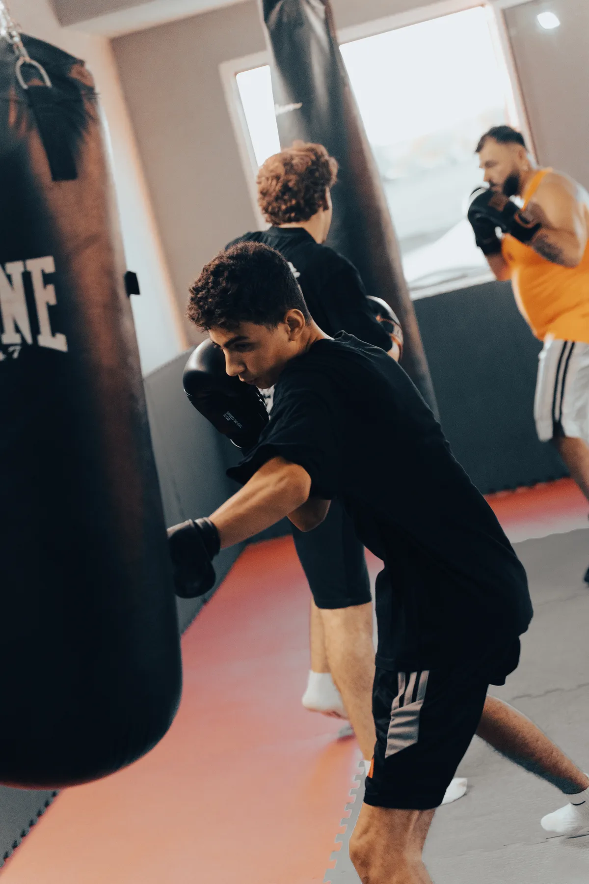 Allievi di pugilato che si allenano al sacco in palestra